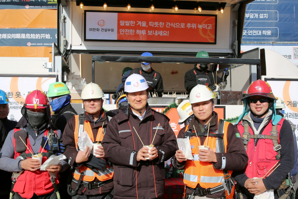 한화 건설부문 김우석 대표이사(가운데)가 건설현장 근로자들과 함께 ‘찾아가는 겨울간식차’의 호빵과 어묵을 즐기고 있다. [사진 = 한화 건설부문]