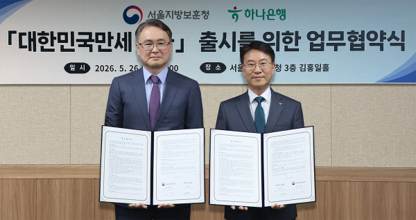 하나은행은 지난 26일 오후 서울 용산구 서울지방보훈청에서 호국보훈의 달을 맞아 ‘대한민국만세 적금’ 출시를 위한 업무협약을 체결했다. 이날 협약식에 참석한 김영호 하나은행 리테일그룹 그룹장(사진 오른쪽)이 이승우 서울보훈청장(사진 왼쪽)과 함께 협약서를 들고 기념촬영을 하고 있다. [사진=하나은행]