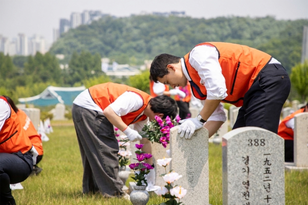 호반그룹 임직원들이 군인 묘역에서 비석을 닦고 있다. [사진=호반그룹]
